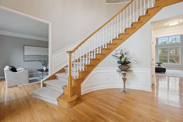 45055 Walnut Rdg, Northville, MI 48168 - staircase featuring hardwood / wood-style flooring, wainscoting, a decorative wall, crown molding, and a towering ceiling