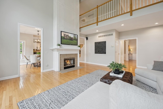 45055 Walnut Rdg, Northville, MI 48168 - living area featuring a towering ceiling, light wood-style floors, a fireplace, baseboards, and recessed lighting