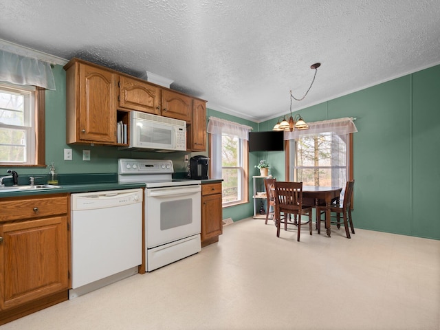 kitchen featuring white appliances, light floors, brown cabinetry, a sink, and a notable chandelier