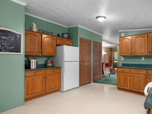 kitchen featuring brown cabinets, freestanding refrigerator, ornamental molding, and light floors