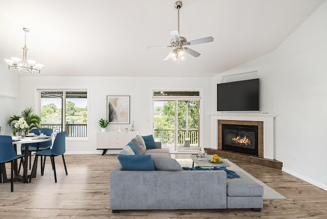 living room featuring a fireplace, lofted ceiling, a wealth of natural light, and wood finished floors