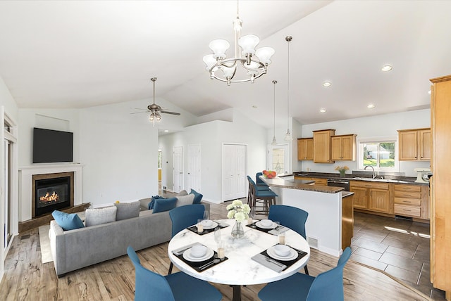 dining area featuring visible vents, light wood-style flooring, recessed lighting, ceiling fan with notable chandelier, and a glass covered fireplace