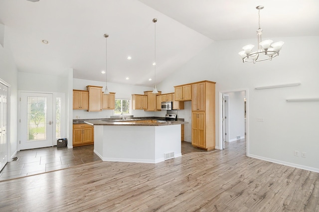 kitchen with a chandelier, light wood finished floors, dark countertops, stainless steel appliances, and visible vents
