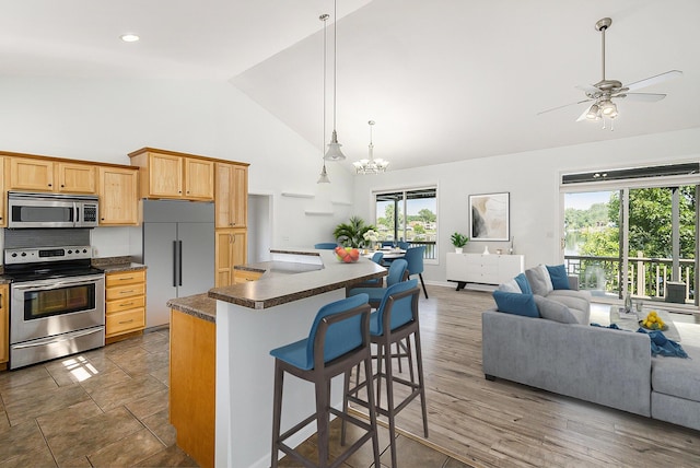 kitchen featuring high vaulted ceiling, a breakfast bar, appliances with stainless steel finishes, open floor plan, and dark countertops