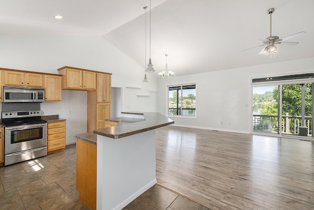 kitchen with high vaulted ceiling, dark countertops, a ceiling fan, appliances with stainless steel finishes, and wood finished floors