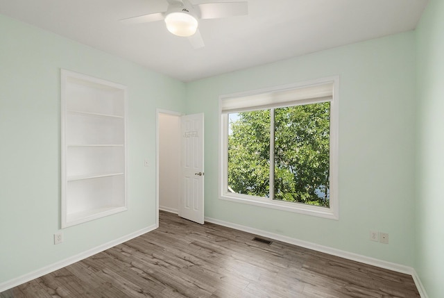 unfurnished bedroom featuring a ceiling fan, wood finished floors, baseboards, and visible vents