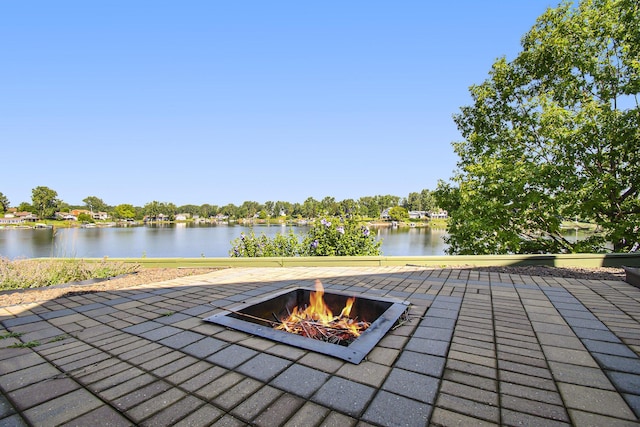 view of patio with an outdoor fire pit and a water view