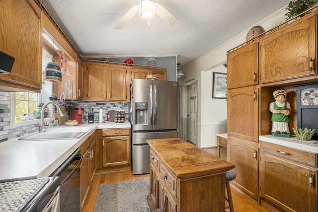 kitchen with ceiling fan, a sink, light wood-type flooring, stainless steel fridge with ice dispenser, and brown cabinetry