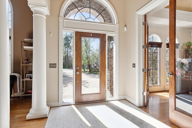 entrance foyer featuring baseboards, decorative columns, and wood finished floors