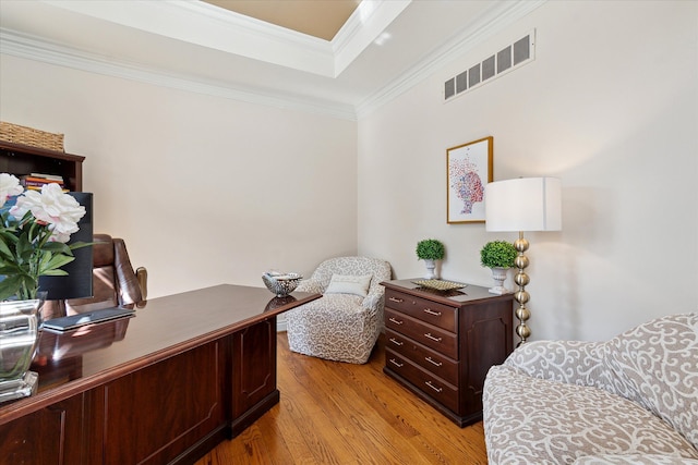 office area with crown molding, a tray ceiling, visible vents, and light wood finished floors