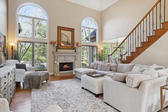 living area featuring a high ceiling, wood finished floors, stairway, and a fireplace