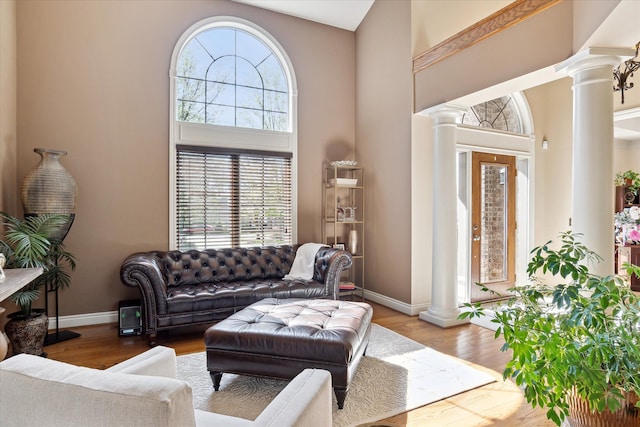 living area with ornate columns, baseboards, a high ceiling, and a wealth of natural light