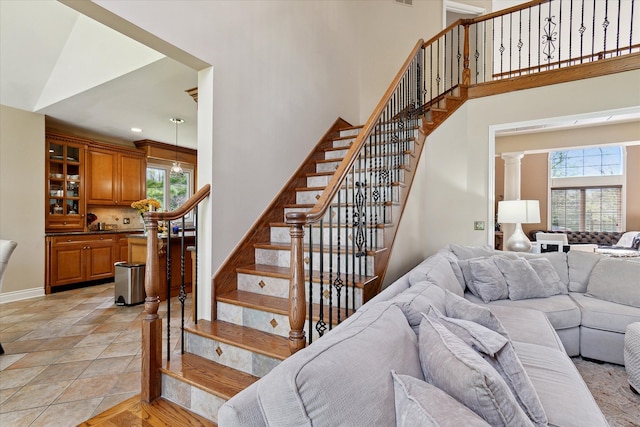 stairs featuring baseboards, a high ceiling, and a wealth of natural light