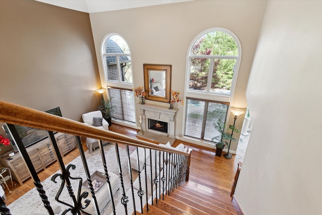 stairway featuring plenty of natural light, a lit fireplace, wood finished floors, and a towering ceiling