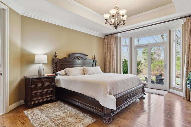 bedroom with baseboards, a chandelier, ornamental molding, and wood finished floors