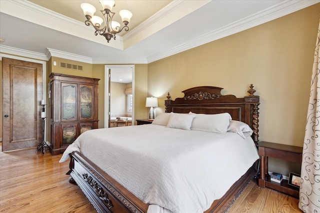 bedroom featuring visible vents, light wood-type flooring, crown molding, and an inviting chandelier