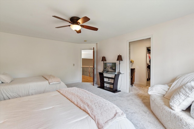 carpeted bedroom featuring a closet, a walk in closet, baseboards, and a ceiling fan