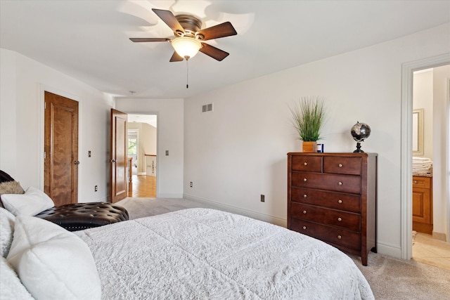 bedroom with ceiling fan, light colored carpet, baseboards, ensuite bathroom, and visible vents