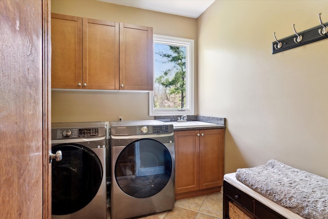 washroom featuring cabinet space, light tile patterned floors, a sink, and washer and clothes dryer
