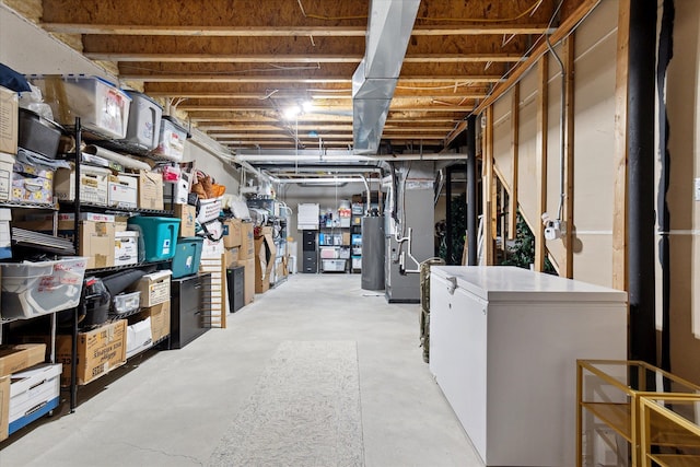 unfinished basement featuring fridge, heating unit, and gas water heater