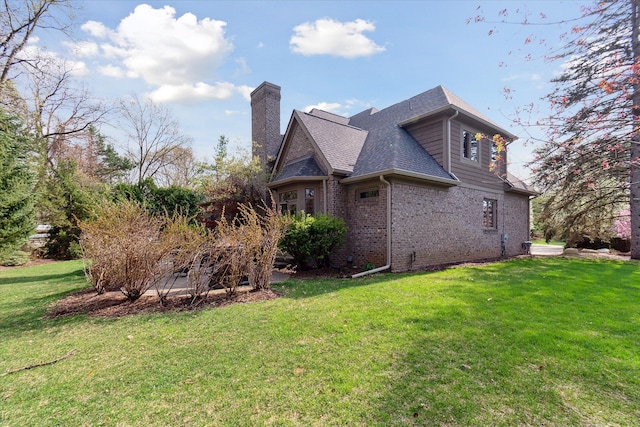 view of side of property with a lawn, a shingled roof, brick siding, and a chimney