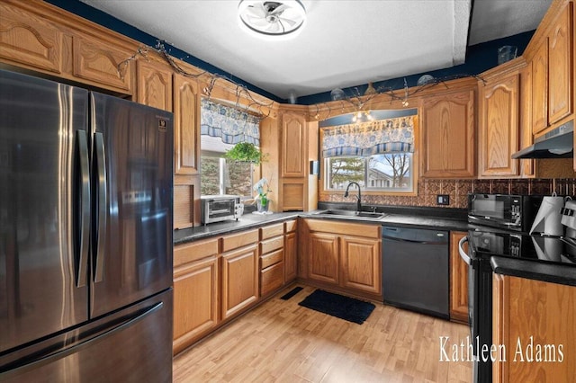 14319 Park Dr, Mecosta, MI 49332 - kitchen with black appliances, under cabinet range hood, light wood-type flooring, brown cabinets, and dark countertops