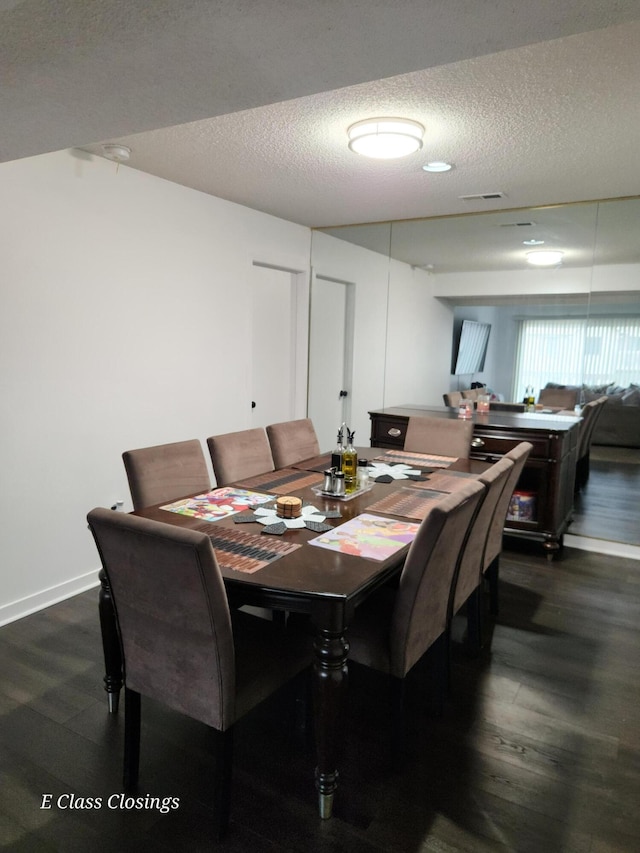 dining space featuring baseboards, visible vents, a textured ceiling, and dark wood-style flooring