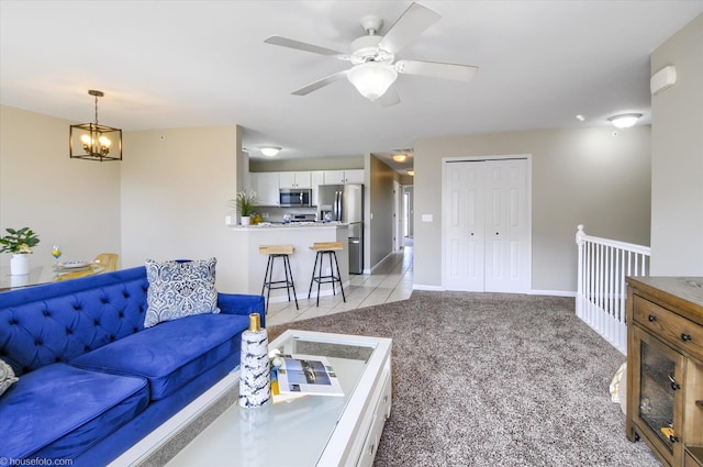 living room with baseboards, ceiling fan with notable chandelier, and light carpet