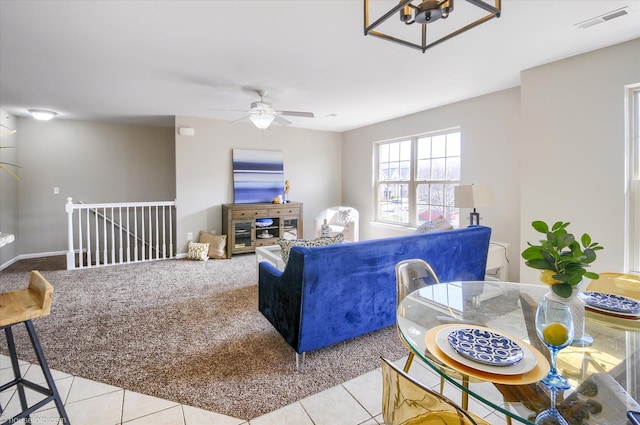 living area featuring light carpet, visible vents, light tile patterned flooring, and a ceiling fan