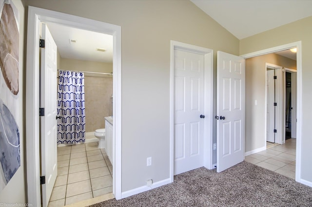 full bath with a shower with shower curtain, baseboards, toilet, vaulted ceiling, and tile patterned flooring