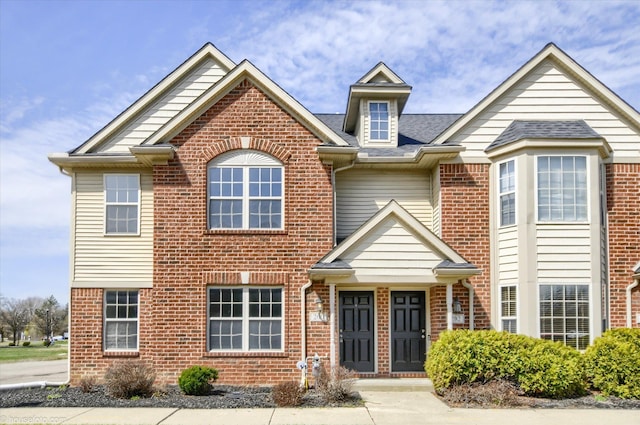 view of front of house with brick siding and roof with shingles