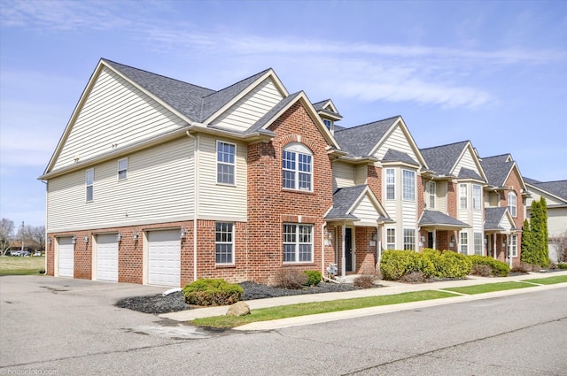 multi unit property featuring brick siding, driveway, and an attached garage