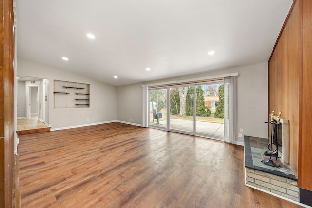 unfurnished living room with baseboards, vaulted ceiling, wood finished floors, and recessed lighting