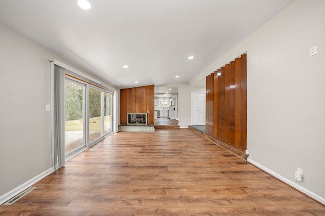 unfurnished living room featuring a large fireplace, visible vents, recessed lighting, lofted ceiling, and light wood-style floors