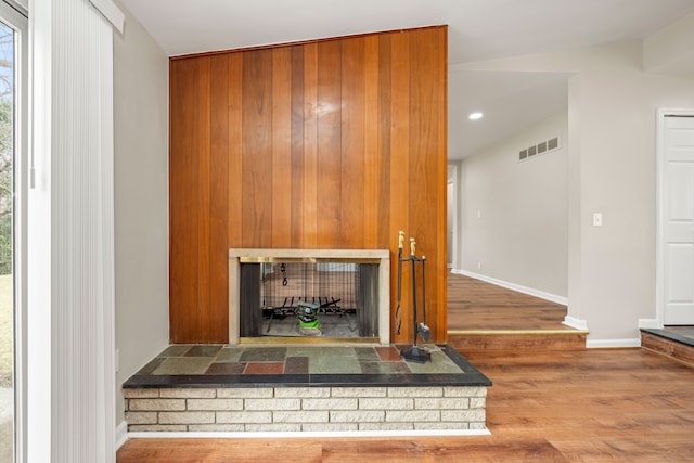 interior details with baseboards, visible vents, wood finished floors, and a fireplace with raised hearth