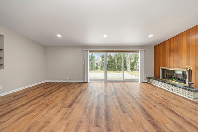 unfurnished living room with baseboards, wood finished floors, recessed lighting, and a brick fireplace