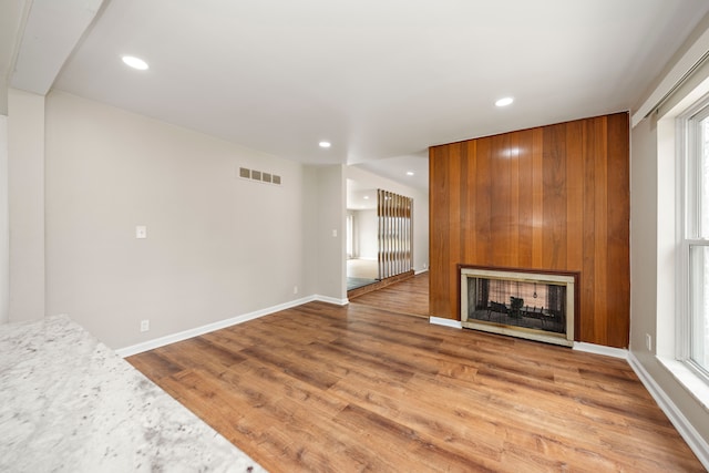 unfurnished living room with recessed lighting, baseboards, a multi sided fireplace, and wood finished floors