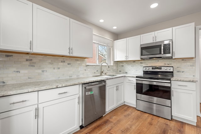 kitchen featuring white cabinetry, a sink, light wood-style floors, and appliances with stainless steel finishes