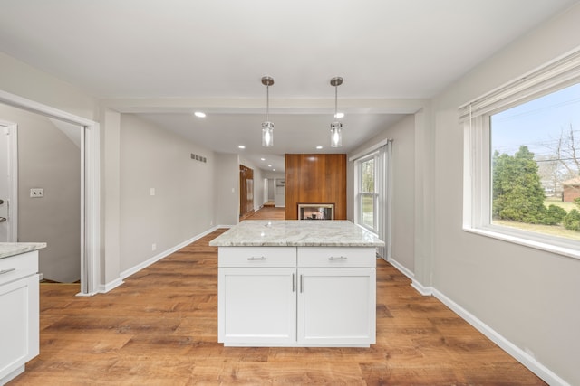 kitchen with hanging light fixtures, baseboards, white cabinetry, and light wood-style flooring
