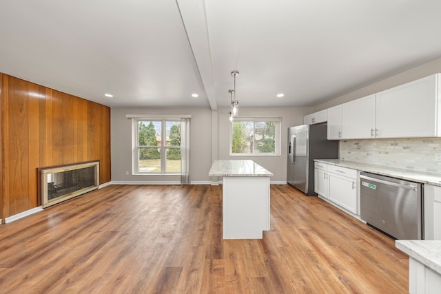 kitchen with decorative backsplash, light wood finished floors, white cabinets, light stone countertops, and appliances with stainless steel finishes