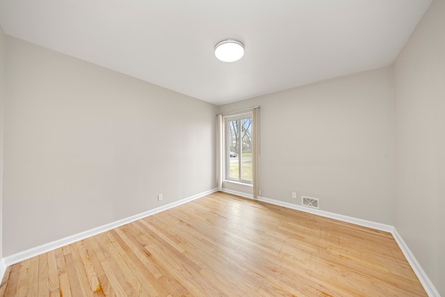 empty room featuring baseboards, visible vents, and wood finished floors