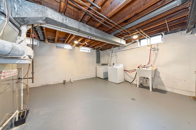 below grade area with a sink, baseboards, washer and dryer, and electric panel
