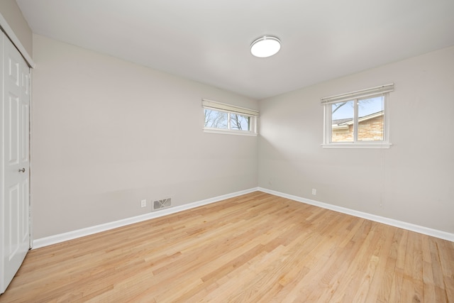 unfurnished bedroom with a closet, baseboards, visible vents, and wood finished floors