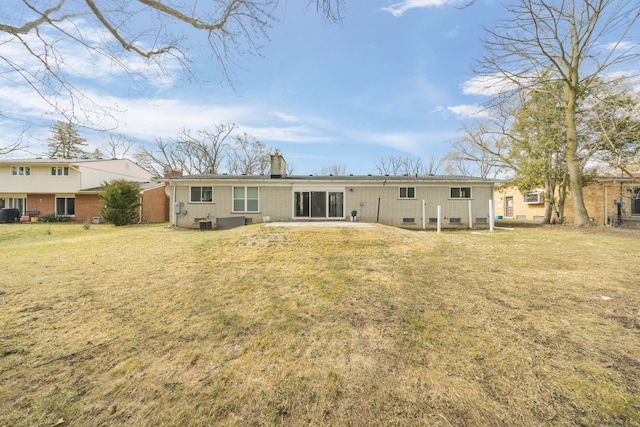 back of house featuring a chimney, central AC, brick siding, and a yard