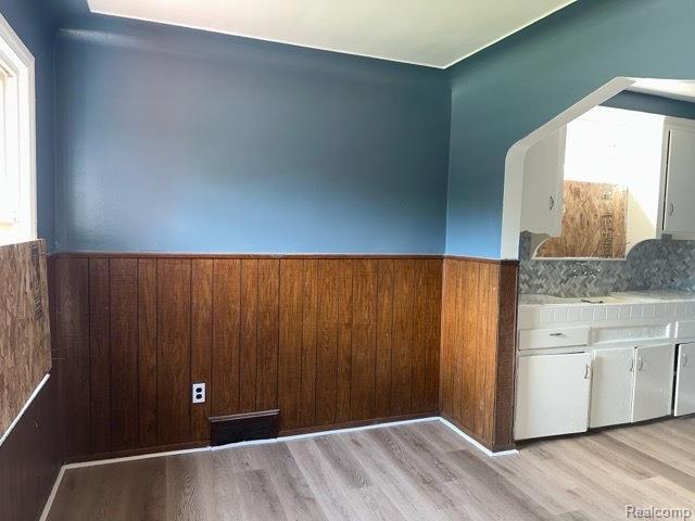 19533 Barlow St, Detroit, MI 48205 - unfurnished room with light wood finished floors, wainscoting, and wooden walls