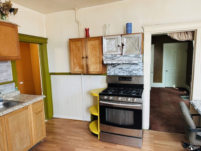1073-1075 Morrell St, Detroit, MI 48209 - kitchen featuring light wood-style floors, light countertops, stainless steel gas range oven, brown cabinets, and baseboards