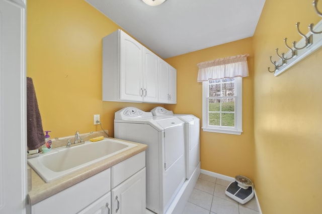 laundry area with washing machine and clothes dryer, baseboards, a sink, cabinet space, and light tile patterned floors
