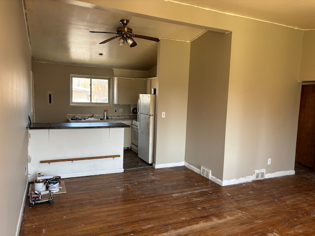kitchen featuring dark wood-style flooring, dark countertops, visible vents, freestanding refrigerator, and a ceiling fan