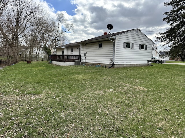 exterior space with a chimney, a wooden deck, and a lawn
