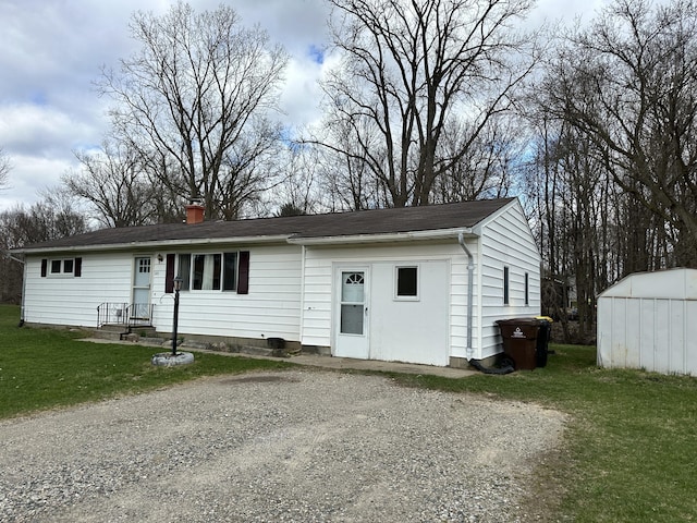 ranch-style home featuring an outbuilding, a storage unit, a front lawn, and a chimney